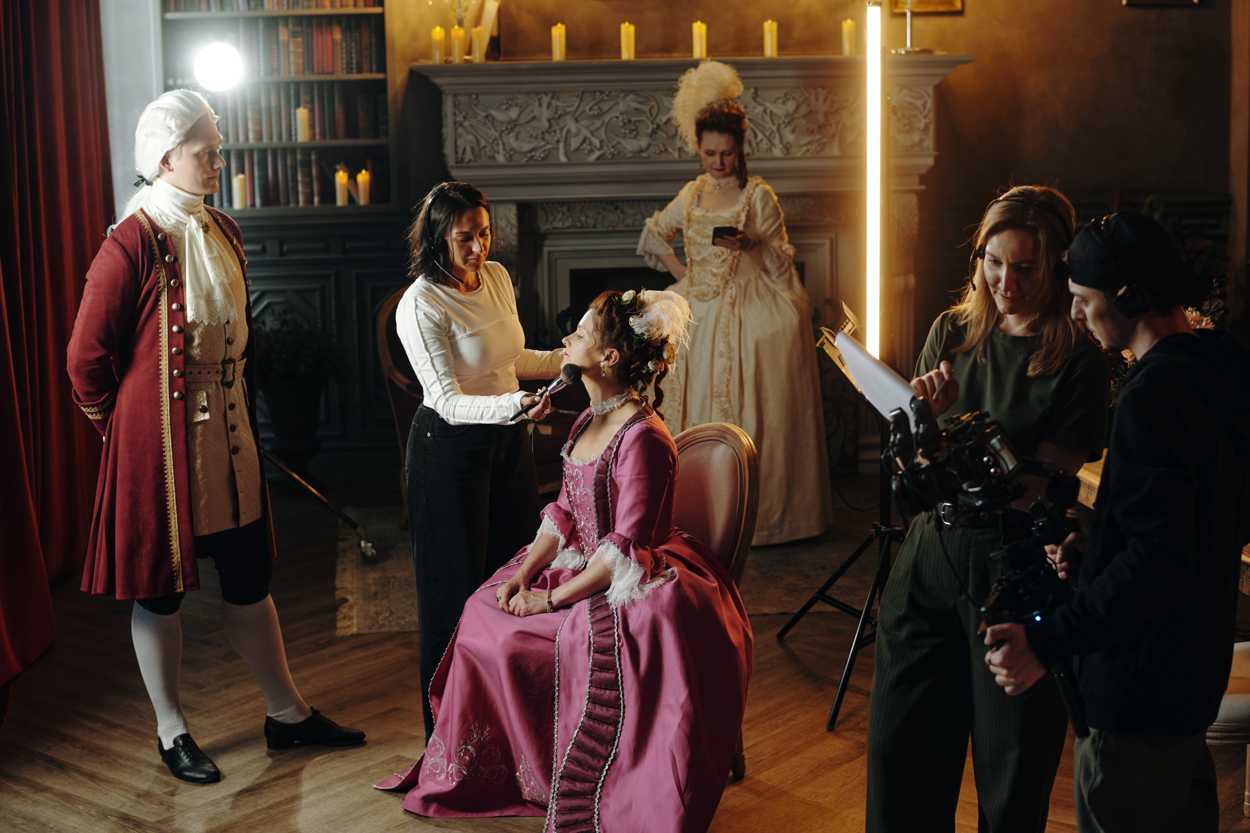 Caucasian Woman in Baroque Costume Preparing for Filming with Crew Assisting