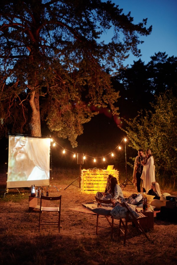 Young friends relaxing and watching movie in the evening in natural environment